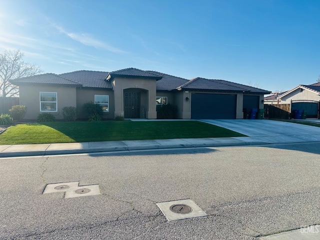 view of front of home featuring a tile roof, stucco siding, concrete driveway, an attached garage, and a front yard