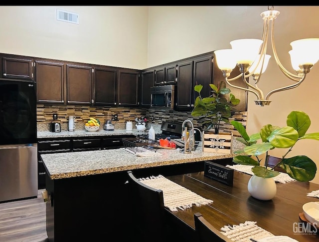 kitchen with pendant lighting, stainless steel appliances, backsplash, and a high ceiling