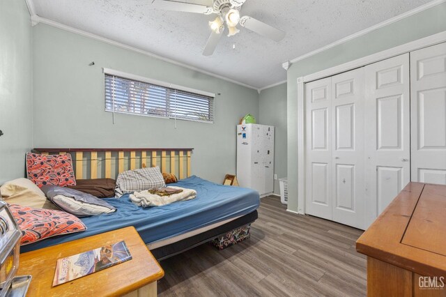 bedroom with wood-type flooring, ornamental molding, a textured ceiling, and a closet