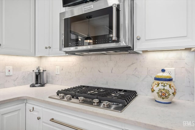 kitchen featuring white cabinetry, appliances with stainless steel finishes, light stone countertops, and backsplash