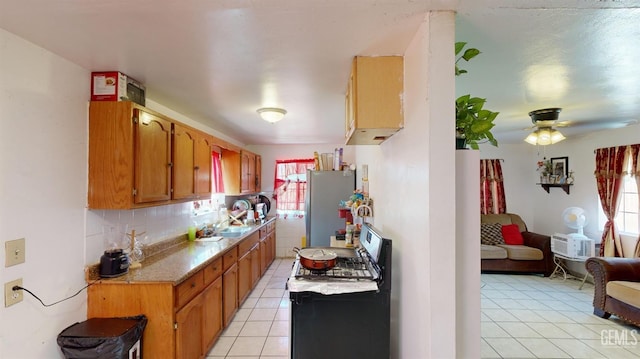 kitchen featuring stainless steel refrigerator, a wealth of natural light, gas range gas stove, and light tile patterned flooring