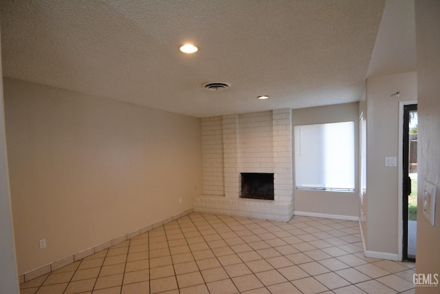 unfurnished living room featuring light tile patterned flooring, a brick fireplace, and a textured ceiling