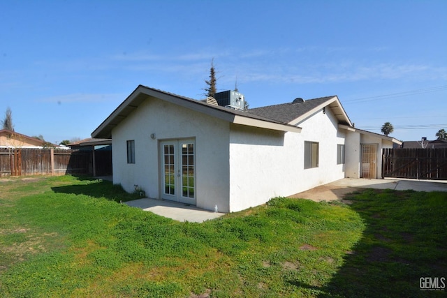 rear view of house featuring french doors, a yard, a patio, and central air condition unit