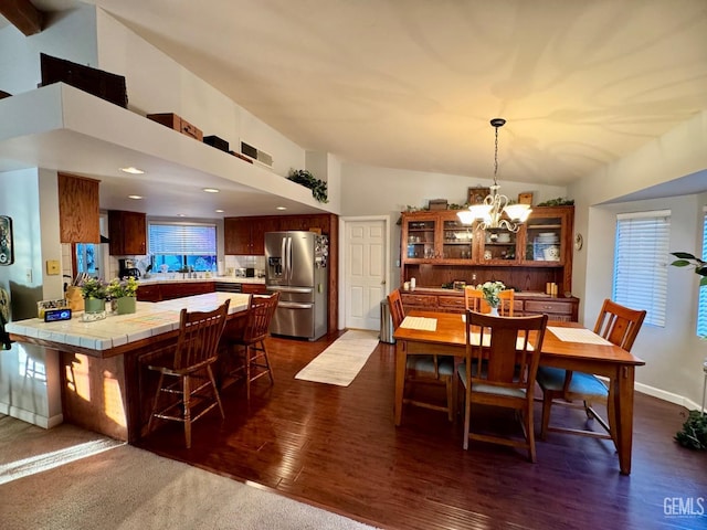 dining space with an inviting chandelier, dark wood-style flooring, and lofted ceiling