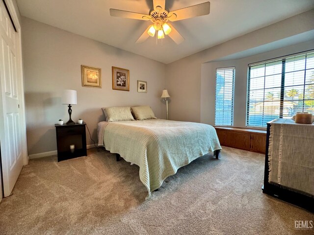 bedroom with a ceiling fan, baseboards, light colored carpet, and a closet