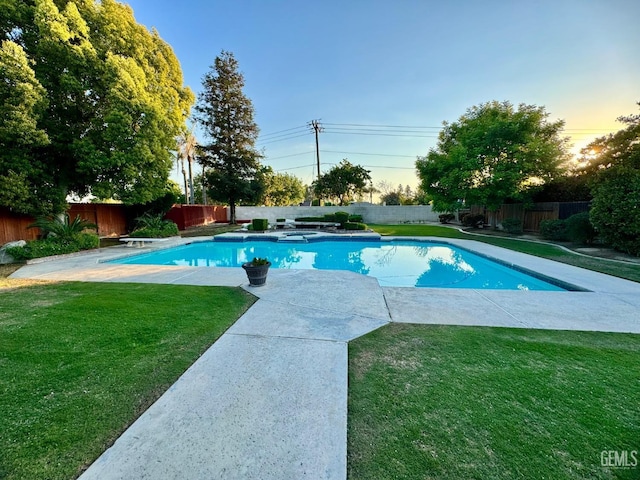 pool at dusk with a fenced in pool, a fenced backyard, a diving board, and a yard