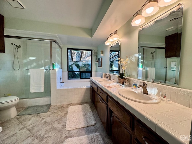 full bath with a sink, a shower stall, toilet, and a bath