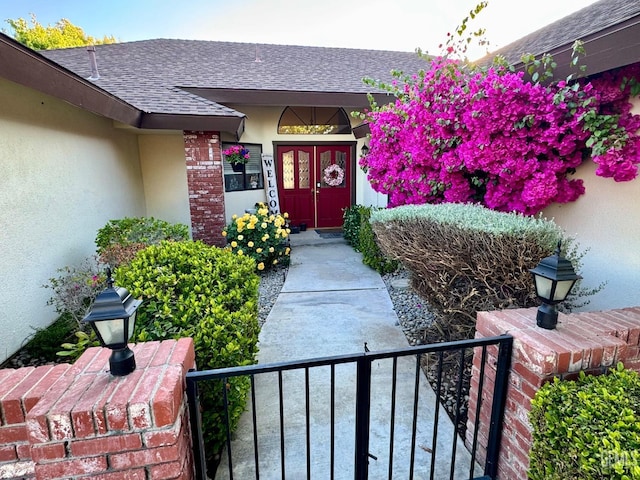 doorway to property with roof with shingles and stucco siding