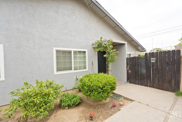 doorway to property with fence, stucco siding, and visible vents
