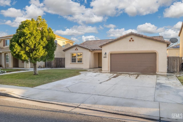 mediterranean / spanish-style home with concrete driveway, a tiled roof, fence, a front yard, and stucco siding