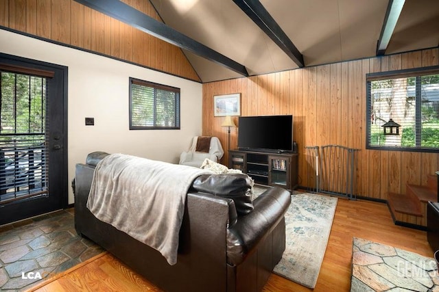 living room featuring vaulted ceiling with beams, hardwood / wood-style flooring, and wooden walls