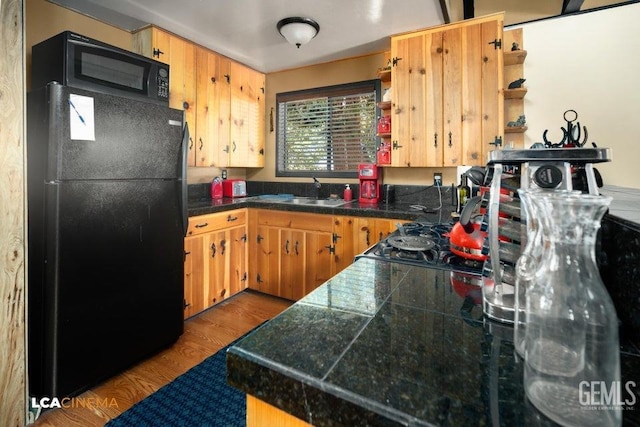 kitchen with black fridge, sink, and light hardwood / wood-style floors