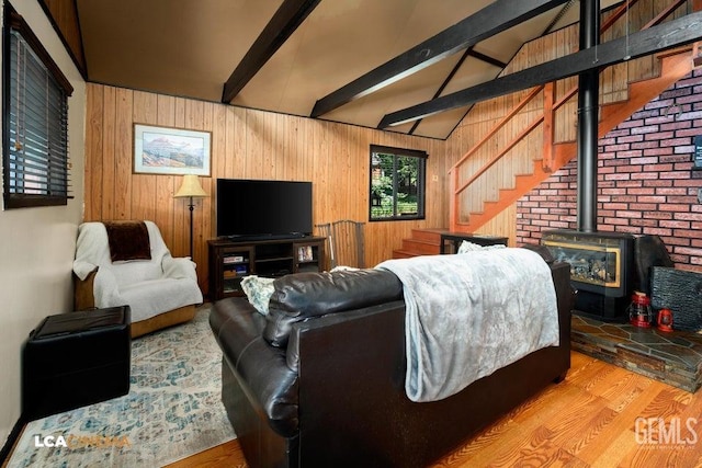 living room with hardwood / wood-style flooring, a wood stove, vaulted ceiling with beams, and wood walls