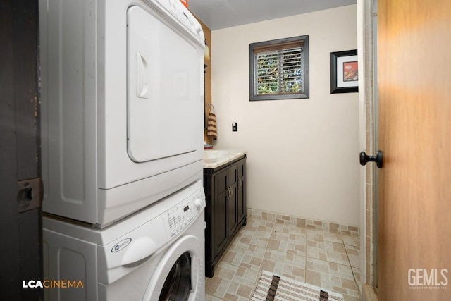 clothes washing area featuring cabinets and stacked washing maching and dryer