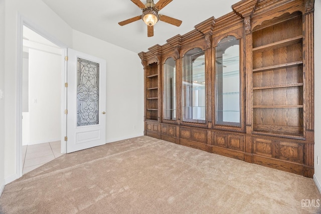 spare room featuring light carpet, light tile patterned floors, and a ceiling fan