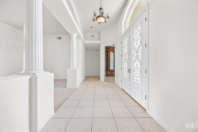 entrance foyer with decorative columns, visible vents, light colored carpet, a chandelier, and light tile patterned flooring