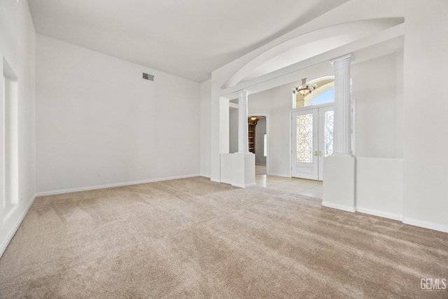 empty room featuring french doors, ornate columns, visible vents, light carpet, and baseboards