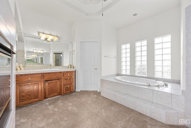 full bath featuring a raised ceiling, carpet floors, vanity, and a bath