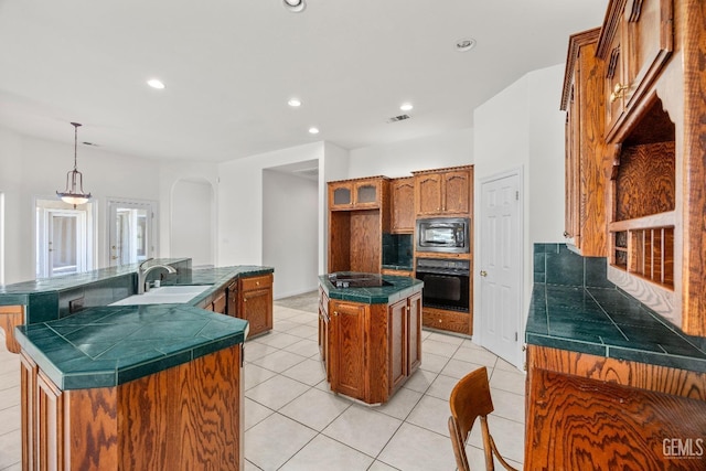 kitchen featuring dark countertops, a kitchen island, brown cabinets, black appliances, and a sink