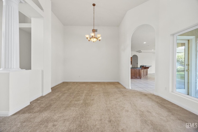 spare room featuring baseboards, an inviting chandelier, arched walkways, and light colored carpet