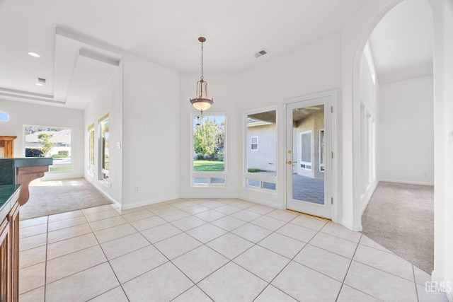 unfurnished dining area featuring light carpet, light tile patterned flooring, and a wealth of natural light