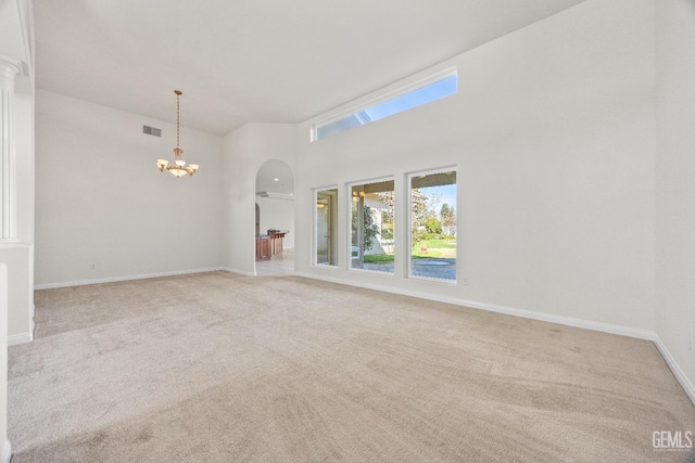 unfurnished room featuring light carpet, baseboards, visible vents, arched walkways, and a notable chandelier