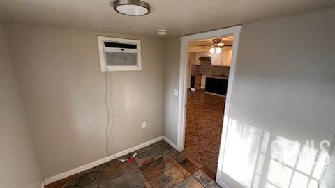 unfurnished room with ceiling fan and an AC wall unit