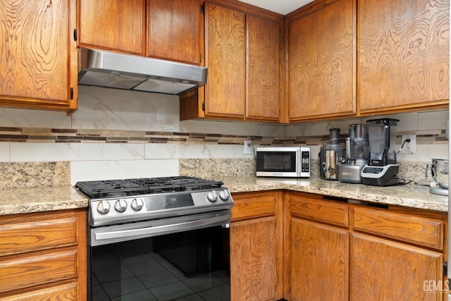 kitchen featuring light stone counters, tile patterned flooring, decorative backsplash, and appliances with stainless steel finishes