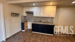 kitchen featuring sink, white cabinets, and backsplash