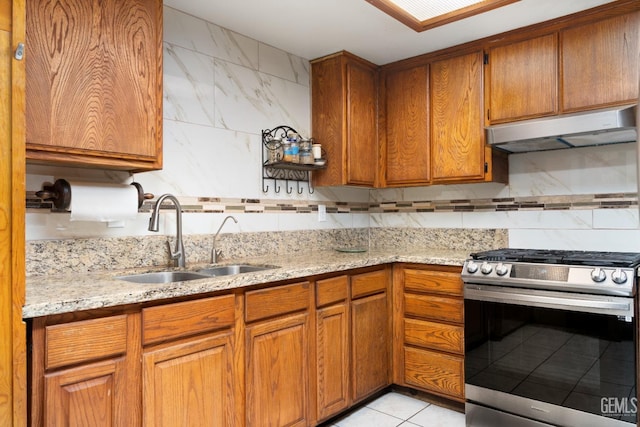 kitchen featuring tasteful backsplash, gas stove, light stone countertops, and sink