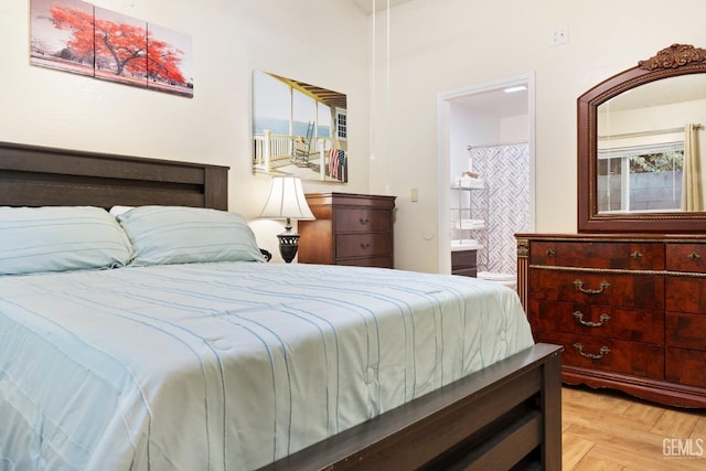 bedroom with ensuite bath and light parquet flooring