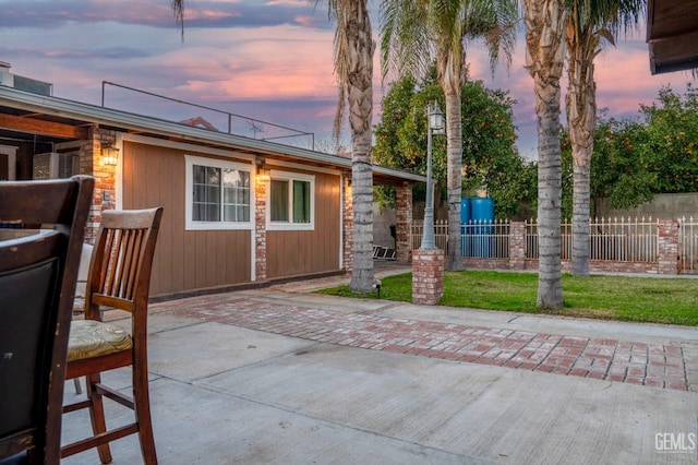 back house at dusk featuring a patio