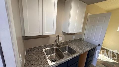 kitchen with sink, light stone countertops, white cabinets, and blue cabinets