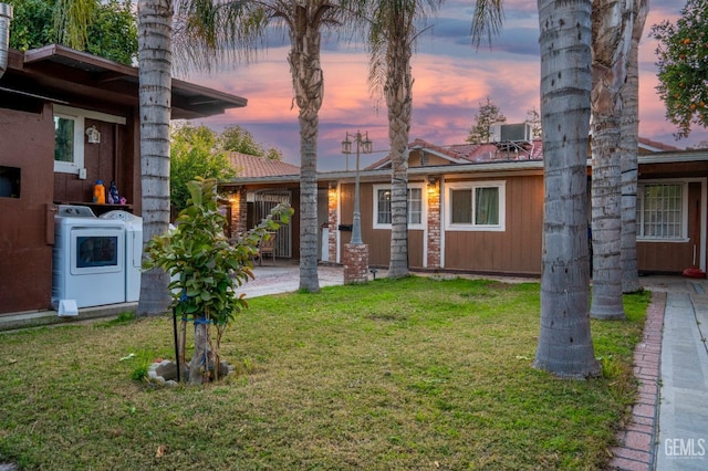 exterior space with a yard, washing machine and dryer, and central air condition unit