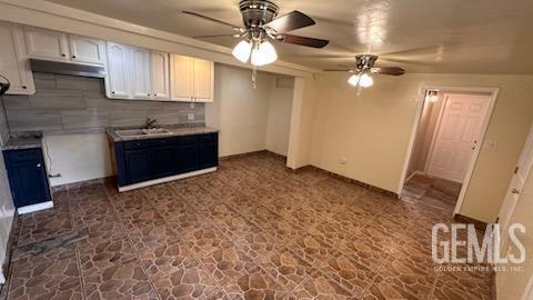 kitchen with tasteful backsplash, sink, white cabinets, and ceiling fan