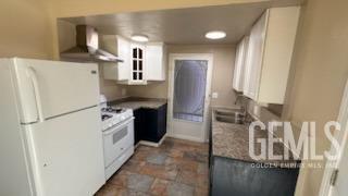 kitchen featuring white cabinetry, sink, wall chimney range hood, and white appliances