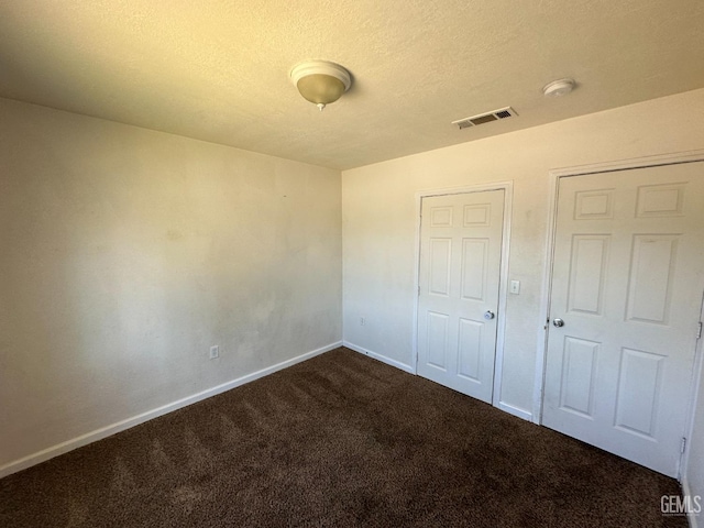 unfurnished bedroom featuring dark carpet and a textured ceiling