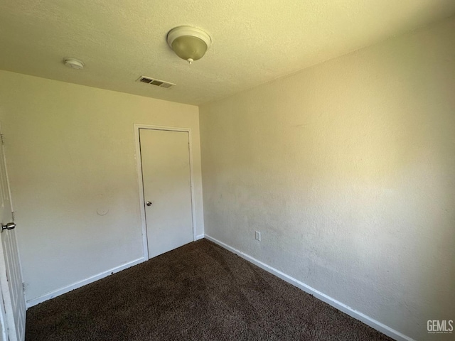 carpeted empty room with a textured ceiling