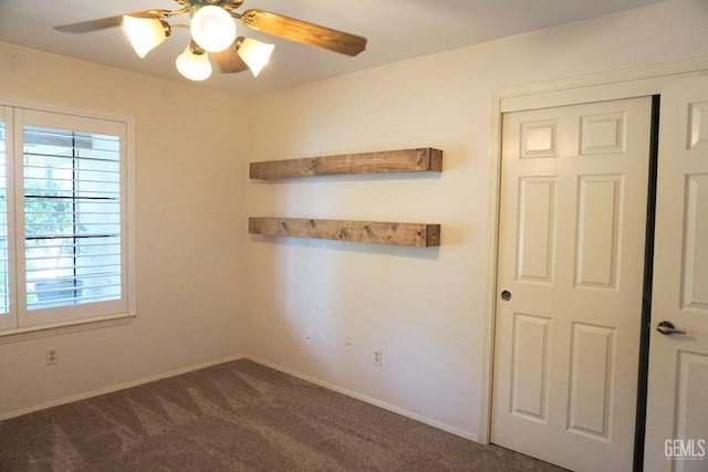 carpeted spare room featuring ceiling fan and baseboards