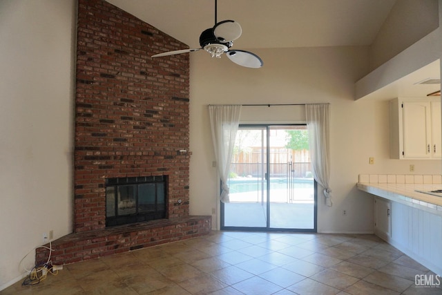 unfurnished living room with a ceiling fan, a fireplace, high vaulted ceiling, and light tile patterned floors