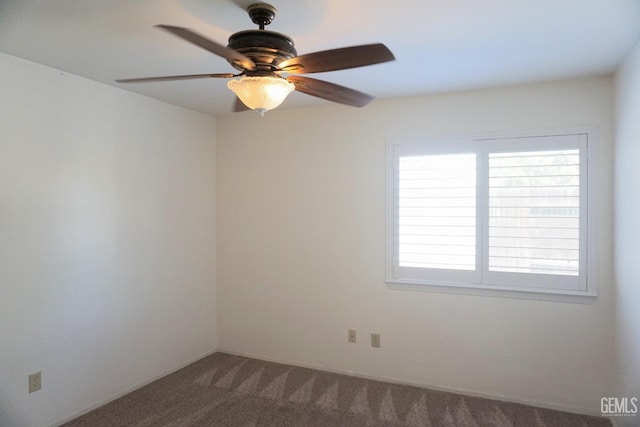 spare room with a ceiling fan and dark colored carpet