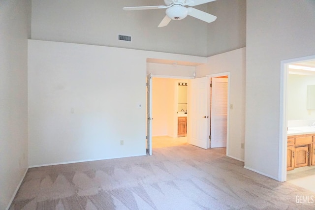 unfurnished bedroom with baseboards, visible vents, light colored carpet, and ensuite bathroom