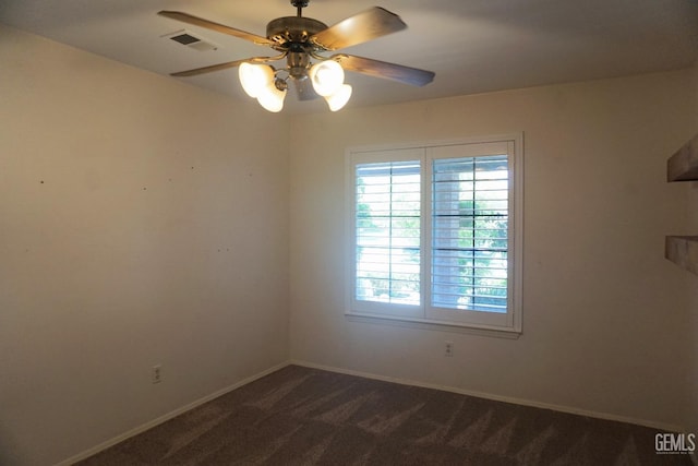 spare room with baseboards, visible vents, dark carpet, and a ceiling fan