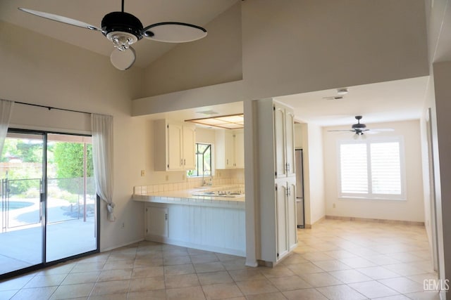 kitchen featuring a healthy amount of sunlight, tasteful backsplash, white cabinetry, and a ceiling fan