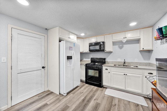 404 Colusa Ave, Chowchilla, CA 93610 - kitchen with black appliances, a sink, white cabinetry, light wood-style flooring, and recessed lighting