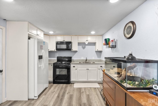 404 Colusa Ave, Chowchilla, CA 93610 - kitchen with black appliances, a sink, white cabinets, light wood-type flooring, and a textured ceiling