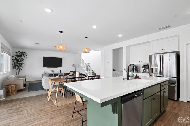 kitchen with wood finished floors, a sink, open floor plan, stainless steel appliances, and visible vents