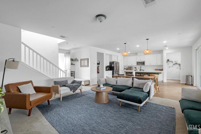 living area featuring visible vents, recessed lighting, and stairway