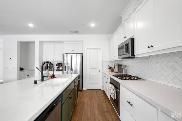 kitchen with stainless steel appliances, a sink, white cabinetry, decorative backsplash, and light countertops
