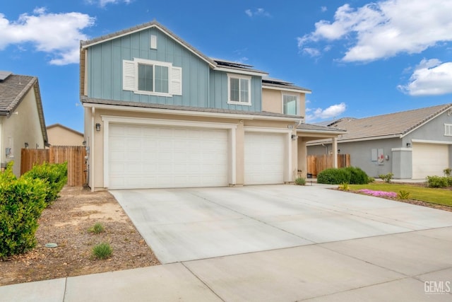 traditional-style home with roof mounted solar panels, fence, board and batten siding, driveway, and a garage